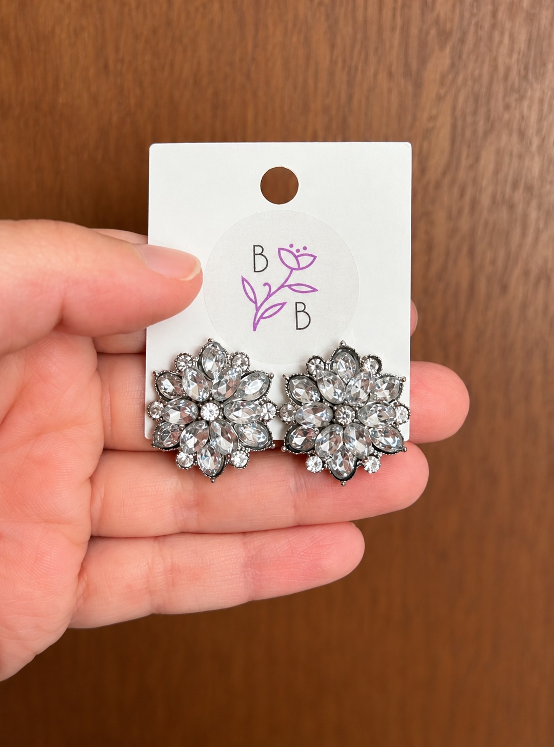 Par de Aretes Fiorella de diseño floral con brillantes transparentes y aleación de tono plateado.