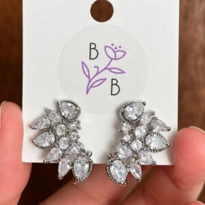 Par de Aretes Seraphine de diseño vegetal alargado en tono plateado y brillantes transparentes.